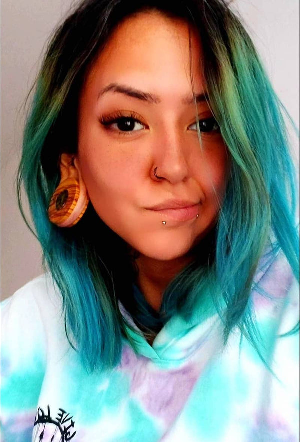 Customer wearing Wild Olive wood ear gauges inlayed with paua stone.